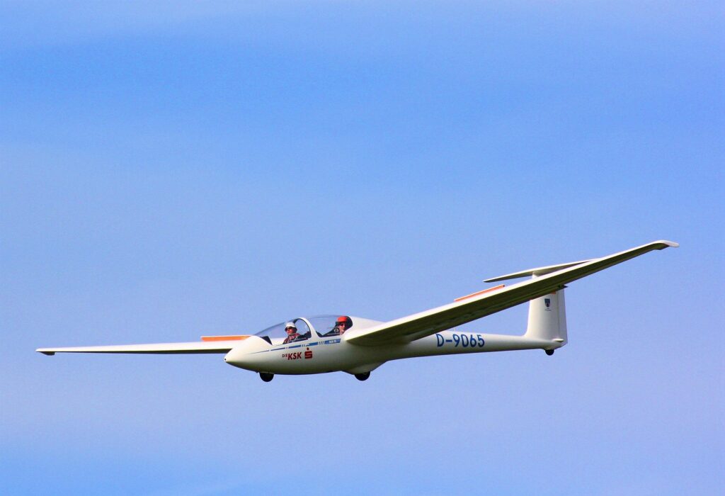A two-seater glider flying gracefully against a backdrop of clear blue sky-Sky Sports 