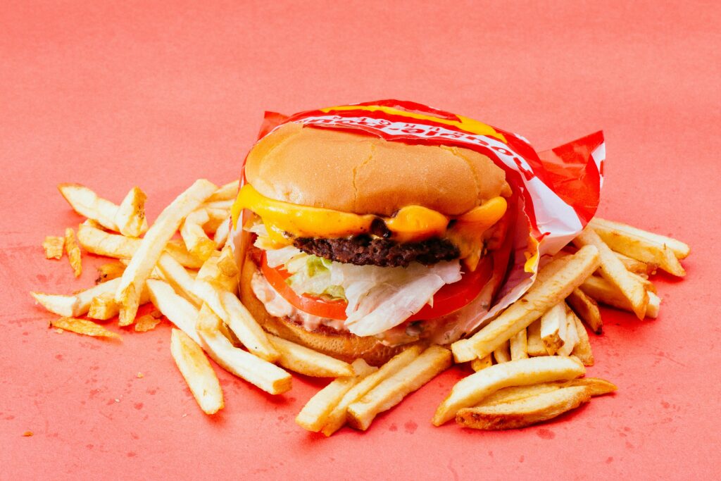Tasty cheeseburger with fresh ingredients and french fries on a vibrant red background.