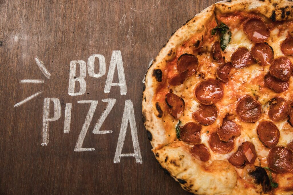 Mouth-watering pepperoni pizza on a rustic wooden table with 'Boa Pizza' text, perfect for food photography.