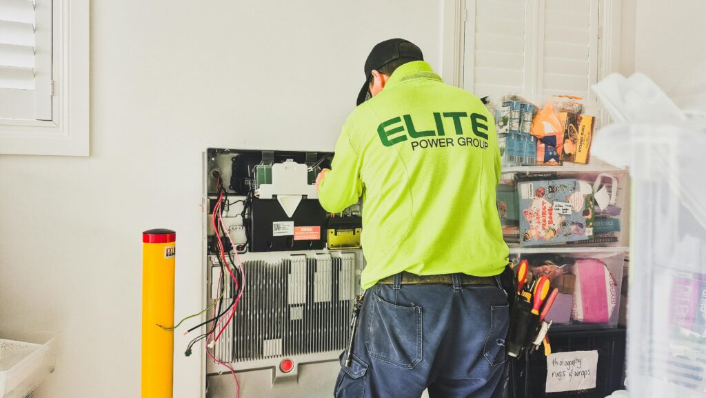A technician from Elite Power Group installing a home battery system indoors in New South Wales, Australia.
