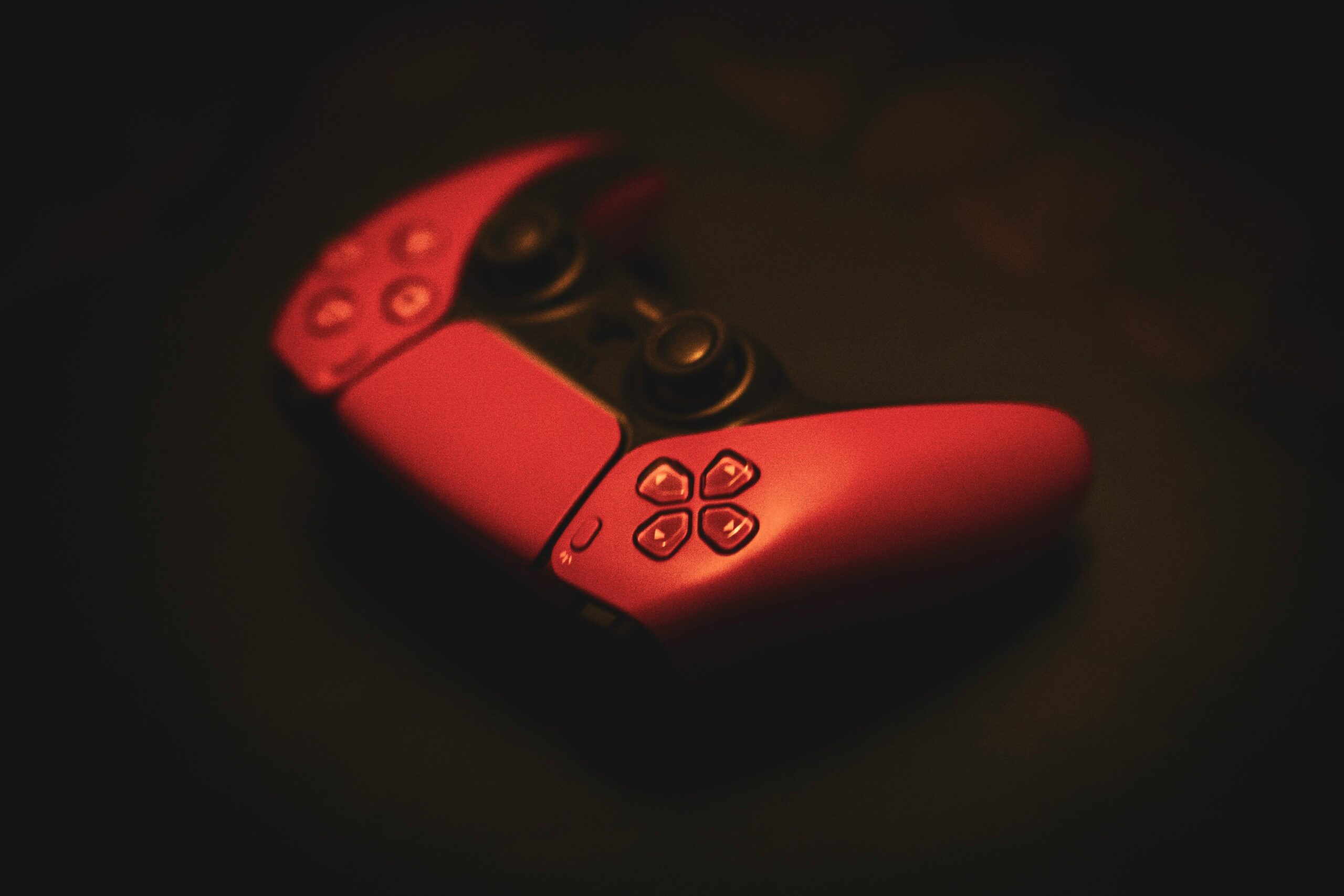 Close-up of a pink gaming controller, highlighting its sleek design in a dark, moody setting.